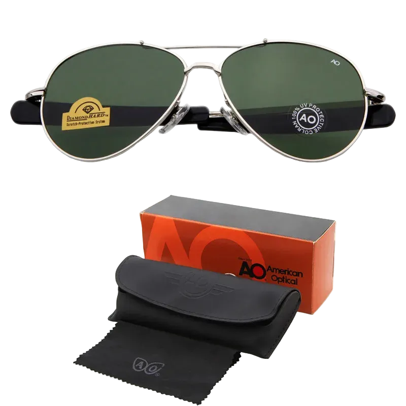 A pair of aviator-style sunglasses with dark green lenses and silver metal frames, shown above their packaging accessories including an orange and black AO box, a black case, and a black microfiber cloth on a white background.