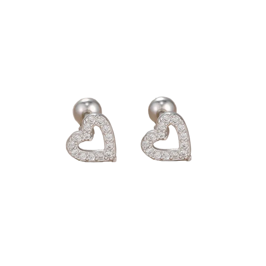 Heart-shaped silver earrings with clear stones on a beige background