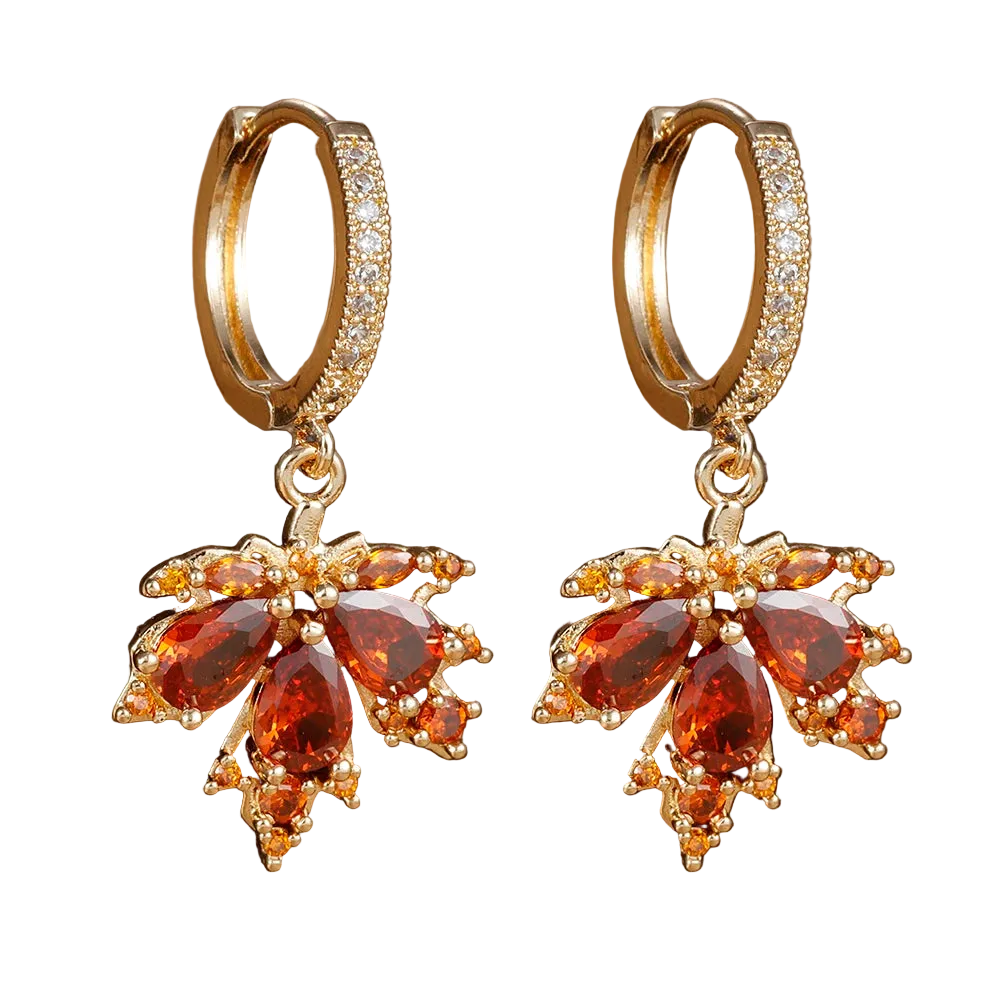 Gold hoop earrings with red gemstones on a brown surface