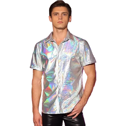A man wearing a short-sleeve iridescent holographic button-up shirt and black pants, standing in front of a shiny silver and purple tinsel curtain backdrop.