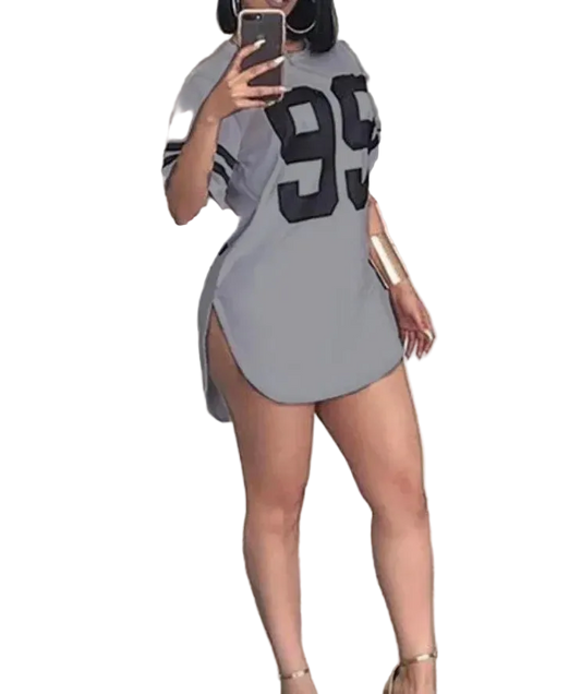 Person wearing a gray dress with large black numbers, taking a mirror selfie.