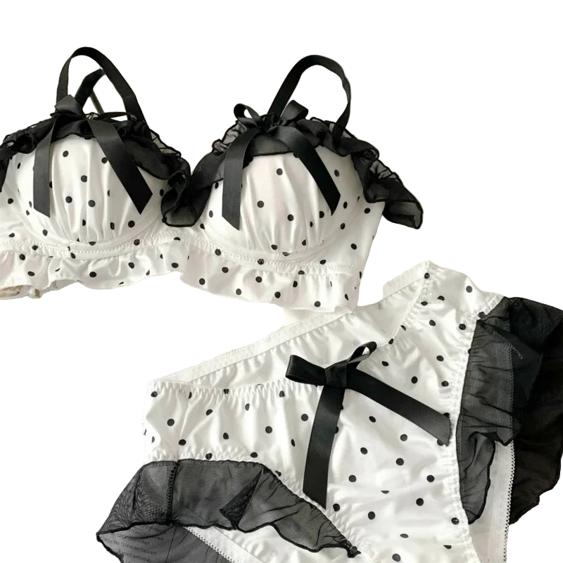 White polka dot lingerie set with black ribbons on a white surface.