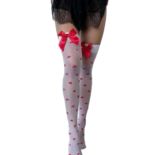 White thigh-high stockings with a red heart pattern and red bow accents at the top, worn by a model in a minimalist studio setting.