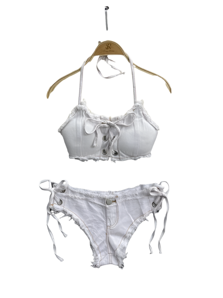 White denim bra and panties set on a textured surface with a pearl-handled bag and flowers in the background.