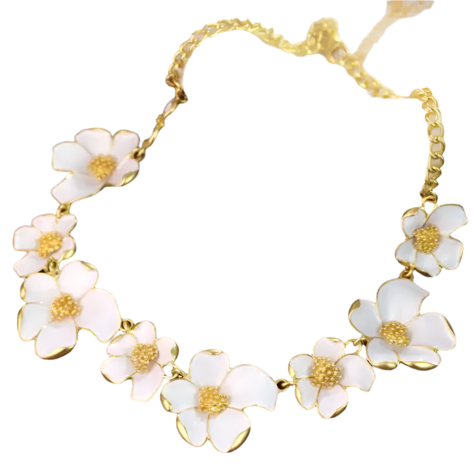 Necklace with white floral pendants and gold accents on a brown surface