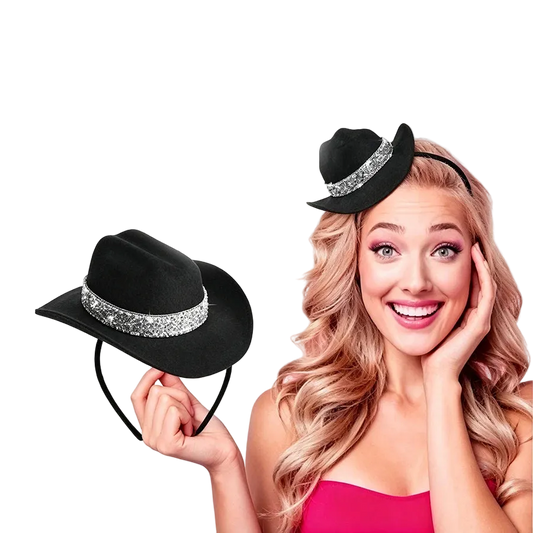A smiling woman with long wavy blonde hair wears a small black hat with a sparkling silver band, while holding the same hat on a headband in her hand against a plain white background.