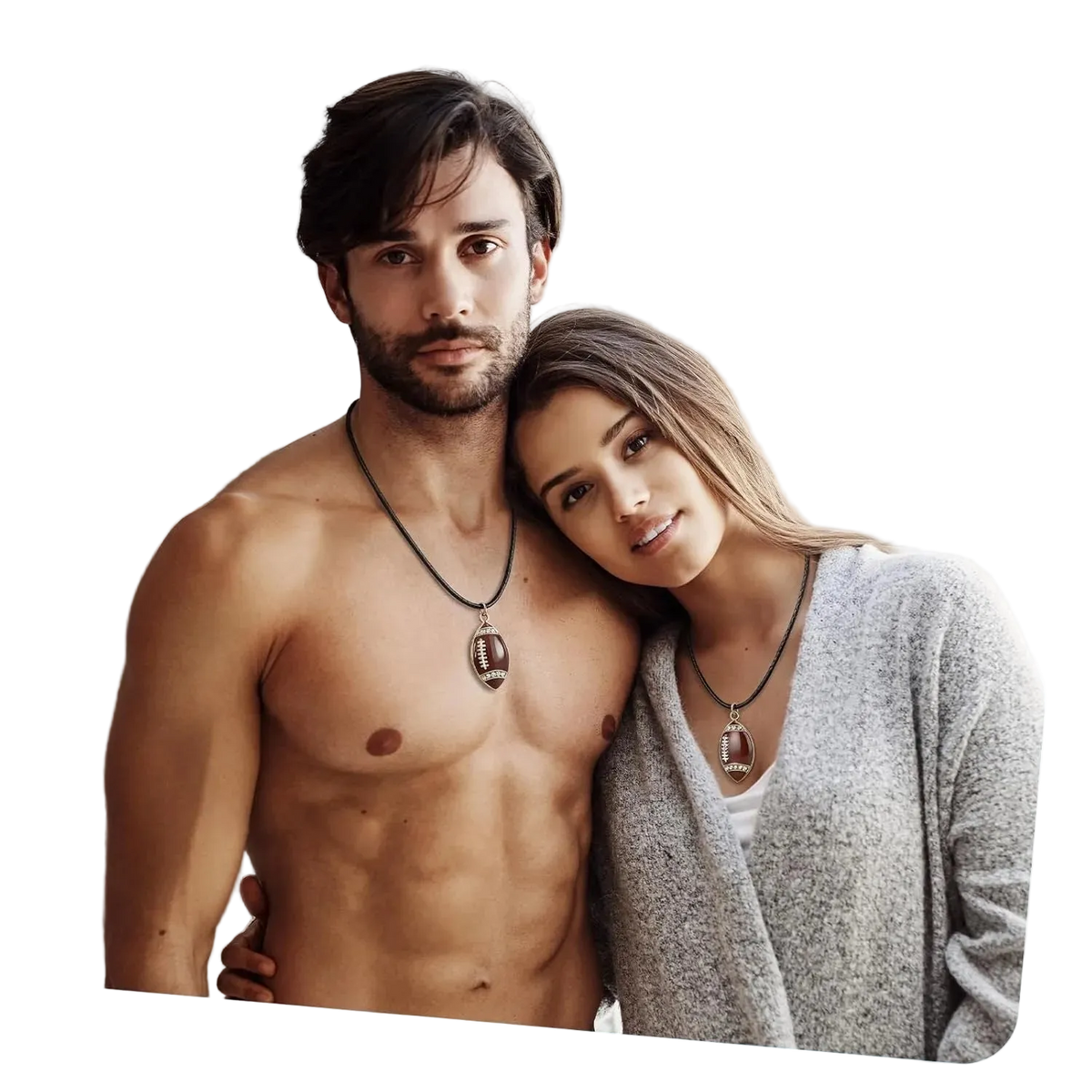 A shirtless man and a woman wearing matching pendant necklaces with football-shaped charms, posed closely together in an indoor setting.