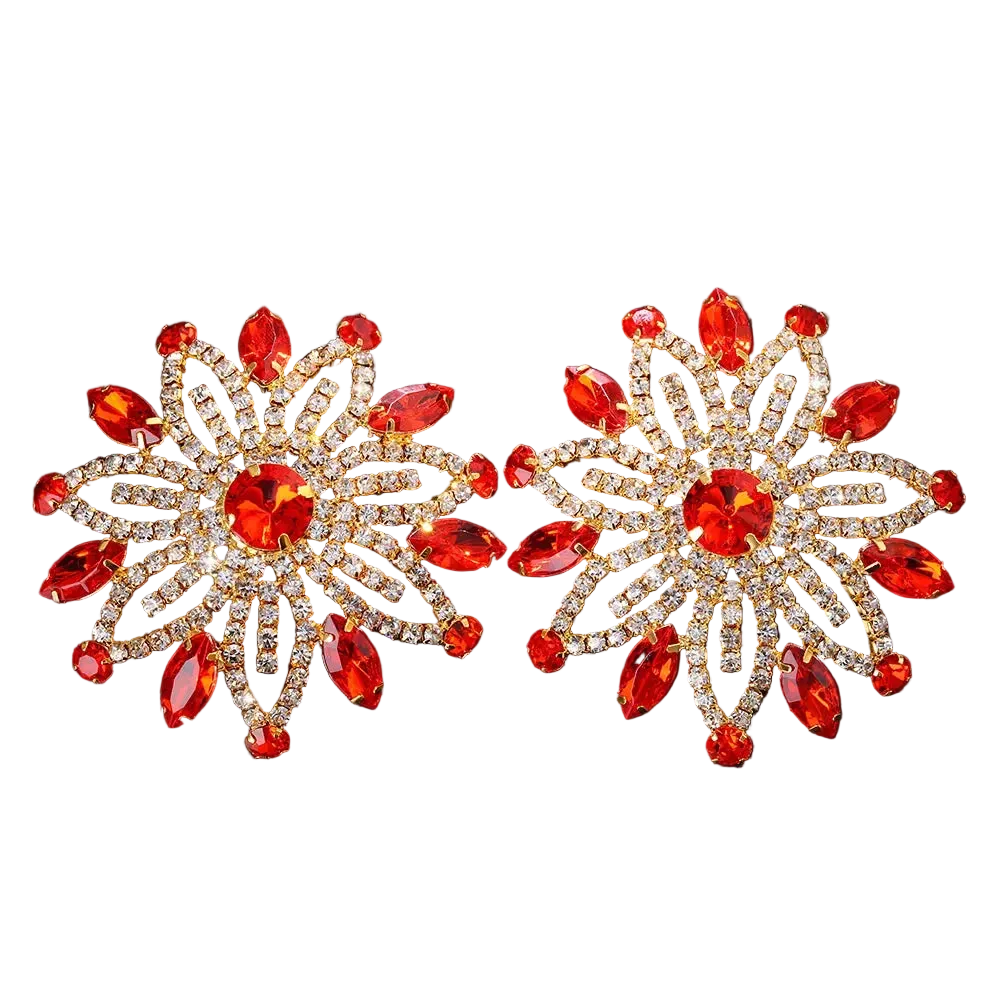 Pair of ornate earrings with red gemstones on a black background