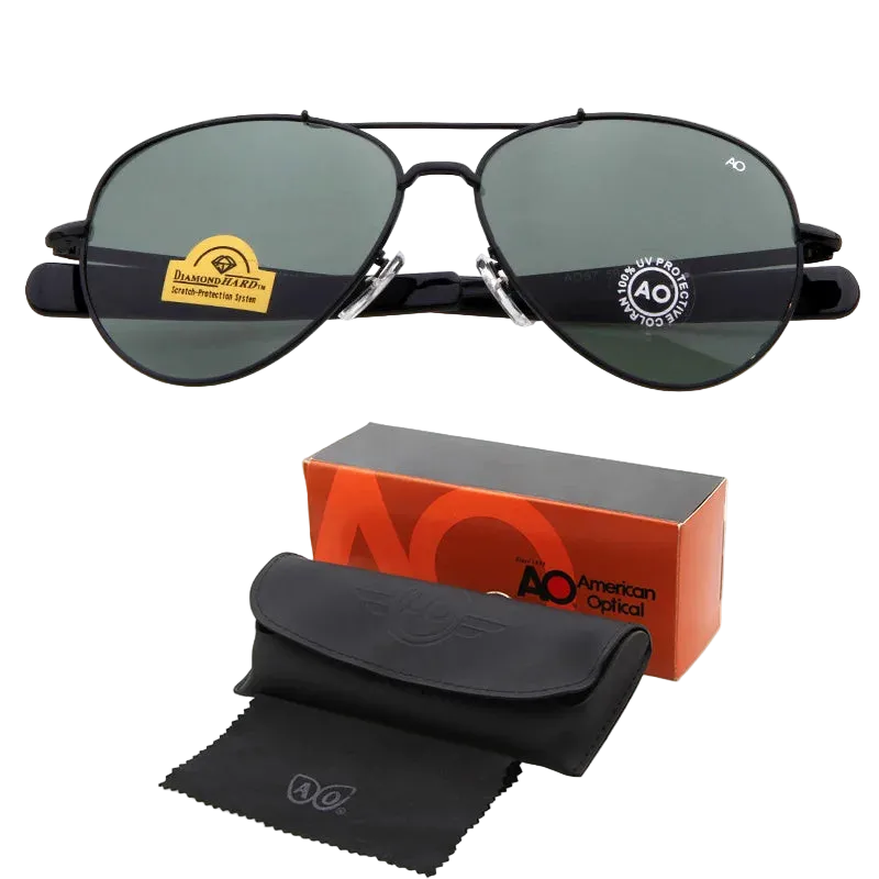 Black aviator sunglasses with dark green lenses, shown with an orange and black AO American Optical box, a black hard case, and a black microfiber cloth on a white background.