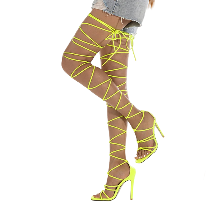 Neon yellow strappy high-heeled shoes worn with sheer stockings on a white background