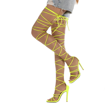 Neon yellow strappy high-heeled shoes worn with sheer stockings on a white background