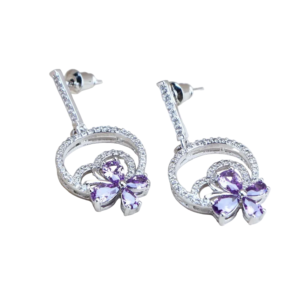Silver earrings with purple gemstones on a light wooden surface, featuring '925 Sterling Silver' text.