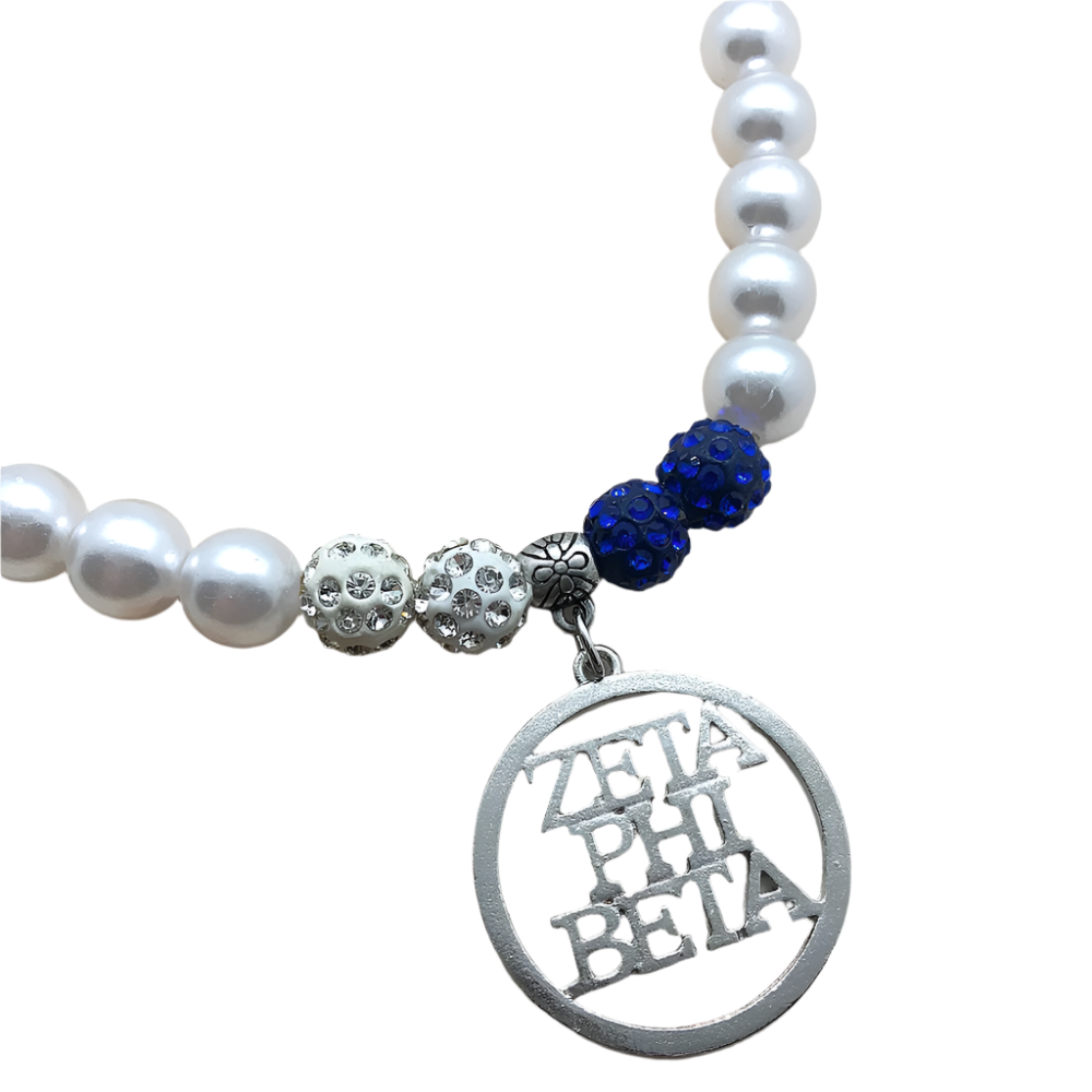 Necklace with white pearls, blue beads, and 'Zeta Phi Beta' charm on a wooden surface