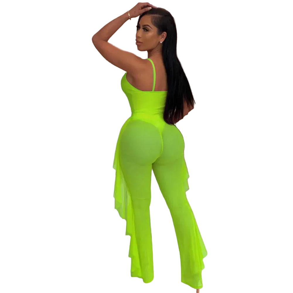 Person wearing a bright green jumpsuit in an indoor setting with plants and a shelf.
