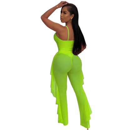 Person wearing a bright green jumpsuit in an indoor setting with plants and a shelf.