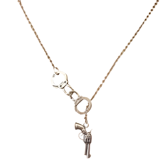 Silver necklace with handcuff and gun charm on a person wearing a white top.