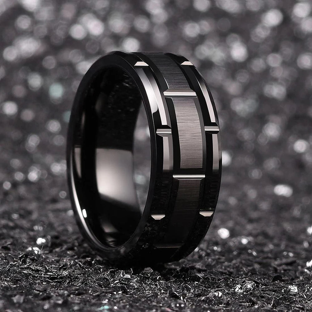 Close-up of the black tungsten ring, highlighting the intricate brick pattern and polished beveled edges.