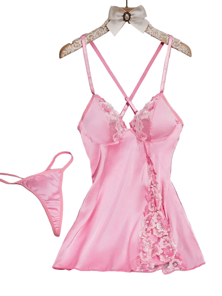 Pink satin nightgown with lace details on a hanger against a white wall.