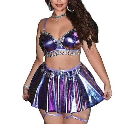 Person wearing a shiny purple outfit with a metallic skirt and top against a silver curtain background.