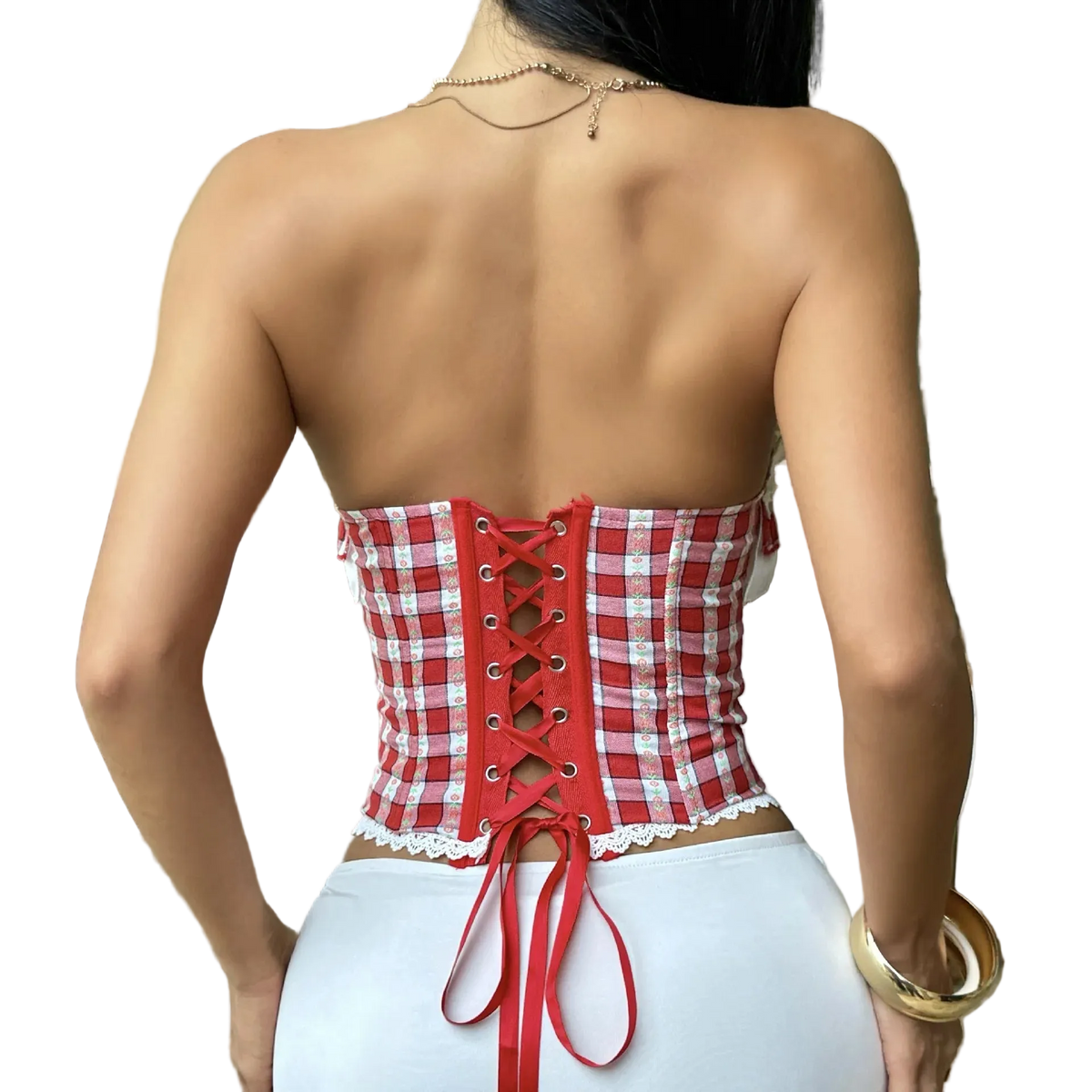 A woman shown from the back wearing a red and white gingham strapless corset top with lace-up back detailing and white bottoms, standing indoors near a patio door and chair.