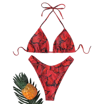 Red snake print bikini set with a straw hat and pineapple on a white background