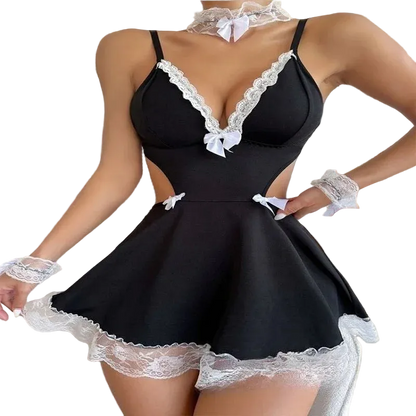 A woman wearing a black lingerie-style mini dress with white lace trim, white lace cuffs, a white lace choker, and small white bows, posed indoors near a window and bookshelf.