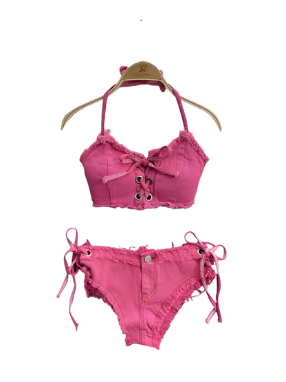 Pink bikini set with lace details on a hanger against a fluffy white surface.