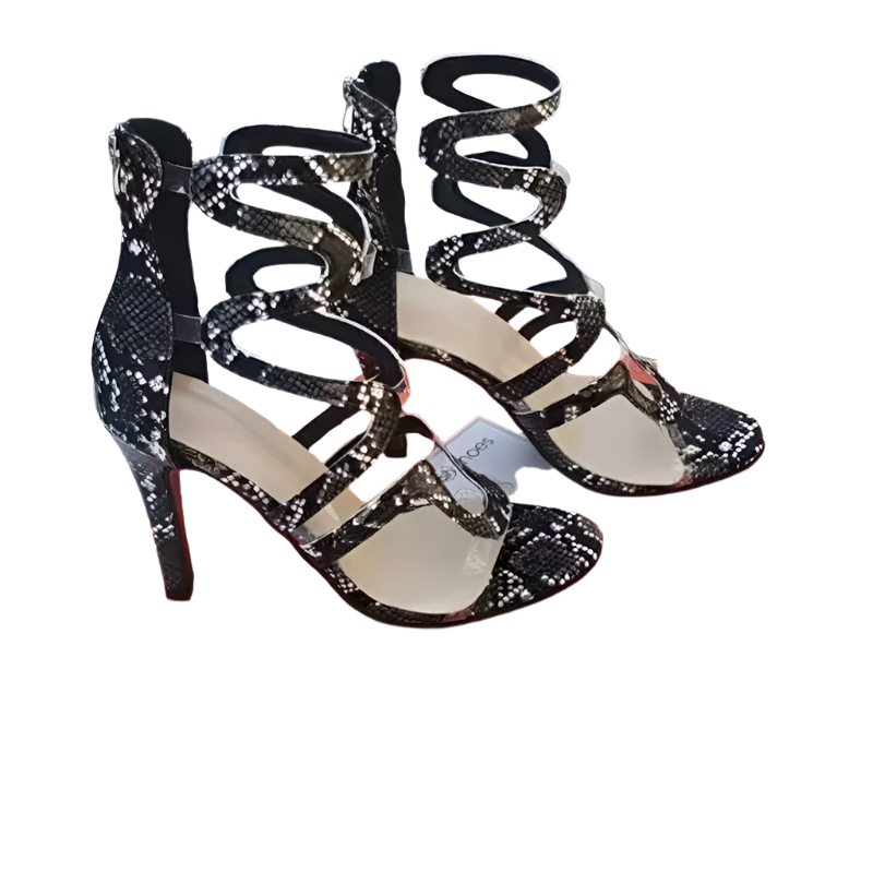 Black and gold strappy high-heeled shoes on an orange shoe box with a blurred background.