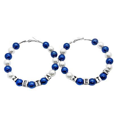 Pair of hoop earrings with blue and white beads and 'ZETA' letter beads on a white background