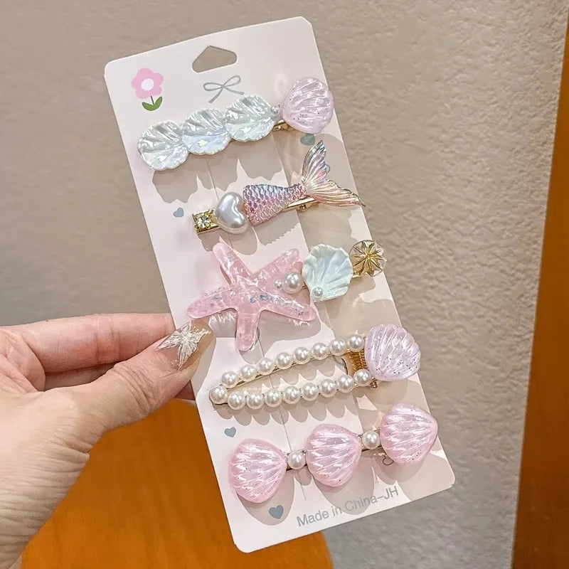 Set of decorative hair clips on a packaging card held by a hand.