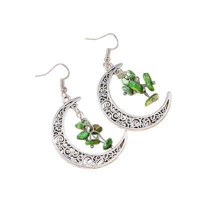 Silver earrings with green beads on a textured stone surface