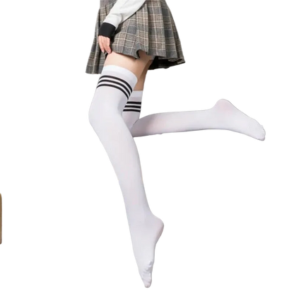 Person wearing white knee-high socks with black stripes sitting on a gray couch.