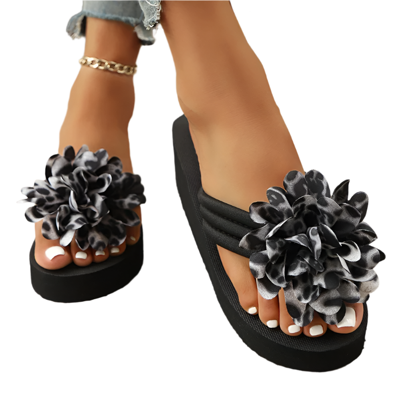 Black sandals with floral designs on a textured floor