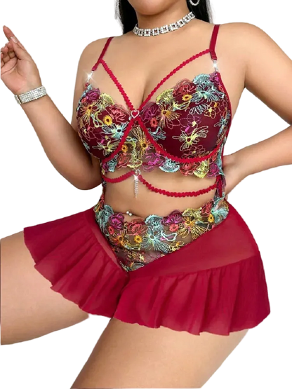 Woman wearing a colorful embroidered lingerie set with red accents on a white background
