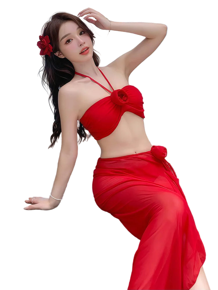 Woman in a red bikini sitting by a beach with tables and chairs in the background.