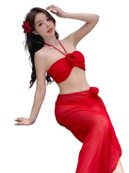 Woman in a red bikini sitting by a beach with tables and chairs in the background.