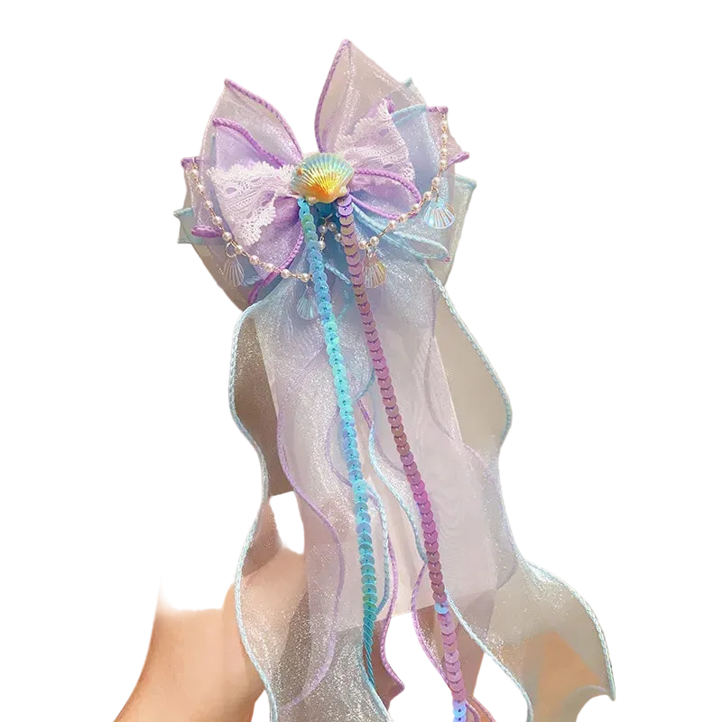 Decorative bow with ribbons held by a person against a neutral background