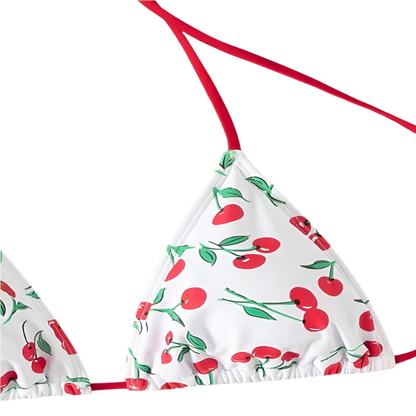 A white bikini with a cherry print. It features a classic triangle top and tie-side bottoms with red strings, giving it a playful and fruity look.
