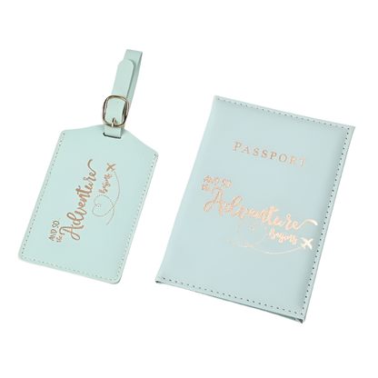 A passport holder and luggage tag set with the phrase "And so the adventure begins" in elegant script. The design is sleek and stylish, perfect for travel.