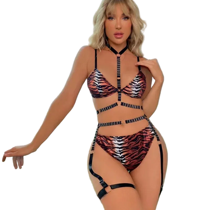 A woman modeling a tiger-print strappy bikini set with matching garter straps, standing by a large window with a city view.