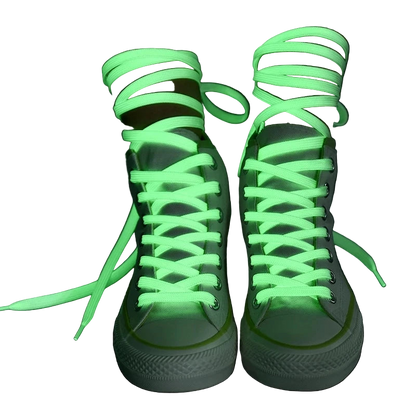 Green fluorescent shoelaces on white sneakers against a dark background
