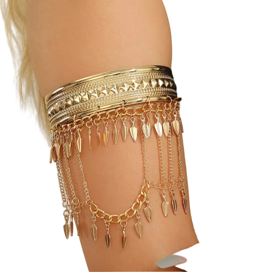 A gold-toned armband jewelry piece with multiple layered chains and dangling leaf-shaped charms, shown worn on a model's upper arm against a light neutral background.