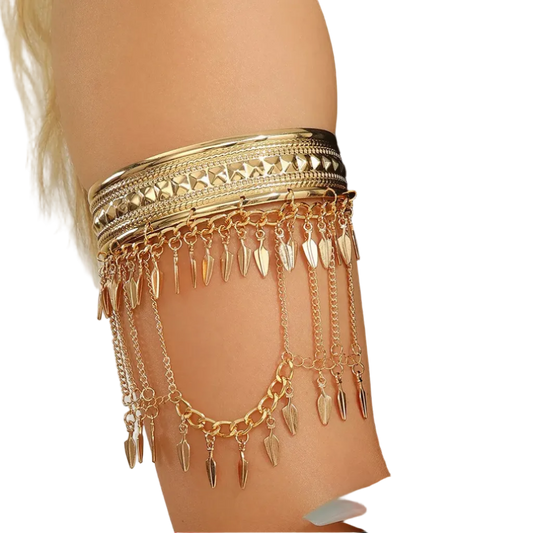 A gold-toned armband jewelry piece with multiple layered chains and dangling leaf-shaped charms, shown worn on a model's upper arm against a light neutral background.