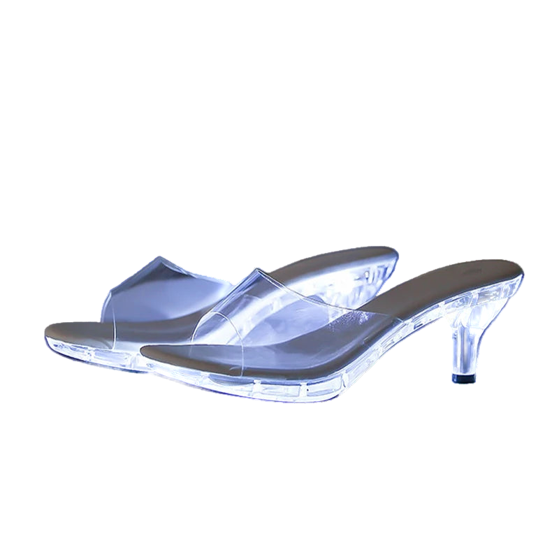 Clear high-heeled shoes with glowing sole on a reflective surface
