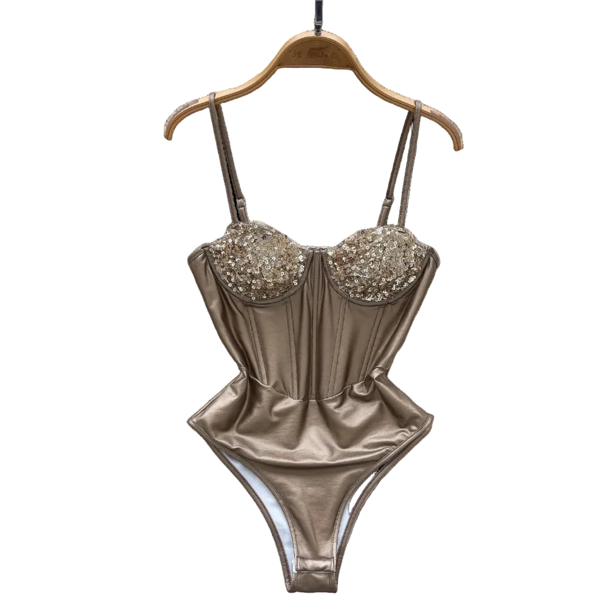Gold swimsuit with embellishments on a hanger against a decorative background with flowers and a hat.