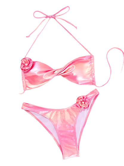 A shiny pink bikini with a wrap-style top and high-waisted bottoms. It includes decorative flower accents on the top and bottom, adding a playful touch.