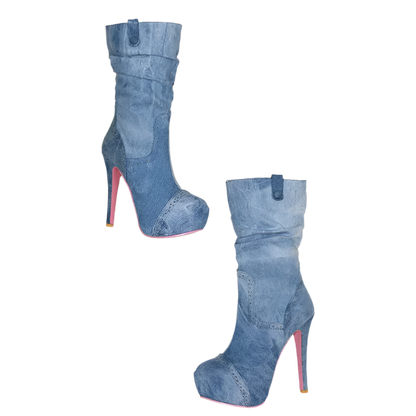 Blue denim high-heeled boots with red soles on a white surface.