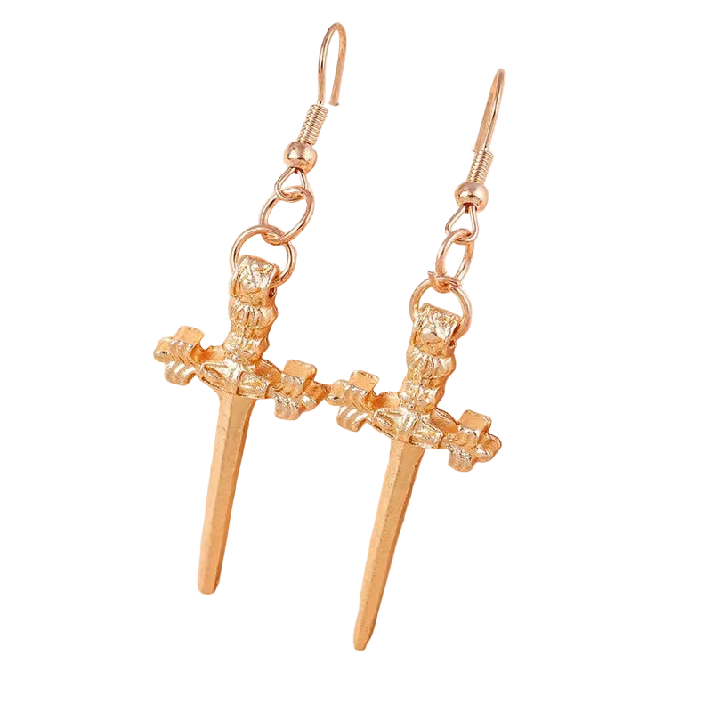 Gold earrings with a spear design on a soft pink background