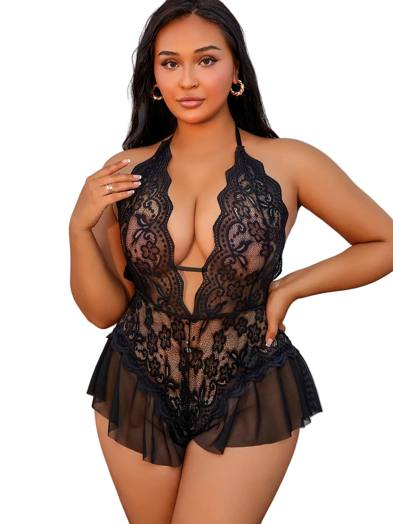 A woman modeling a black lace and sheer mesh halter bodysuit with ruffled shorts in an indoor setting with a white paneled wall and a wooden cabinet.