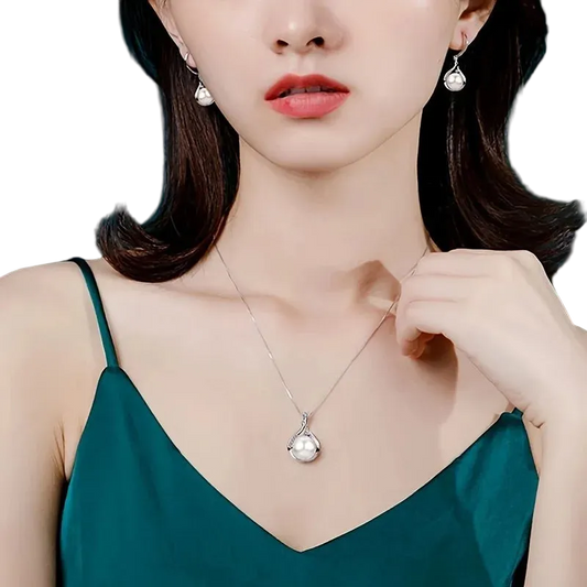 Woman wearing a silver necklace and earrings against a teal background